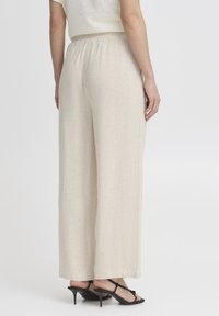Pantalons larges beige avec une taille élastique. Fabriqués en matériau léger, avec une texture lisse et une coupe ample et décontractée.