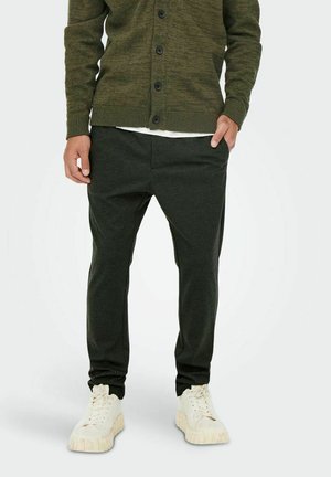 Olive green ribbed cardigan with buttons, paired with dark green tapered joggers featuring side pockets, worn with white cushioned sneakers.