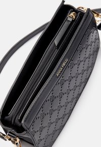 Borsa a tracolla in pelle nera quilted con zip dorata e scritta a logo, caratterizzata da un motivo circolare in rilievo e una tracolla sottile con hardware dorato.