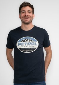 Marine katoenen t-shirt met korte mouwen, voorzien van een ronde witte, blauwe en zwarte graphic met bergafbeeldingen en de tekst "PETROL BIG LAKE ALASKA."