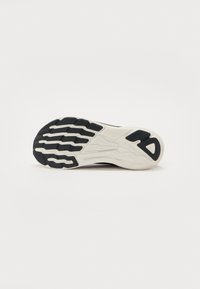Black and white sneaker sole with textured rubber pattern, featuring a prominent, curved heel and grooves for traction on a white background.