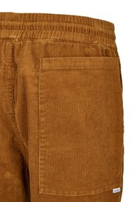 Pantalon en velours côtelé marron avec taille élastique et grande poche latérale affichant une petite étiquette blanche de la marque Clepto.