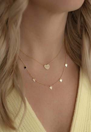 Collane a strati in oro con un ciondolo a forma di cuore inciso con la parola "Amore" e pendenti triangolari. Catena lavorata con una finitura lucida.