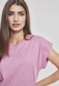 T-shirt in cotone rosa chiaro con maniche corte arrotolate e scollatura rotonda. Tessuto morbido e vestibilità rilassata, caratterizzato da dettagli minimi.