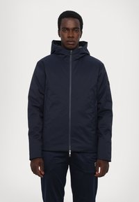 Giacca con cappuccio blu navy con chiusura a zip, dotata di tasche laterali e un tessuto liscio e isolante per mantenere caldo. Design semplice, vestibilità moderna.