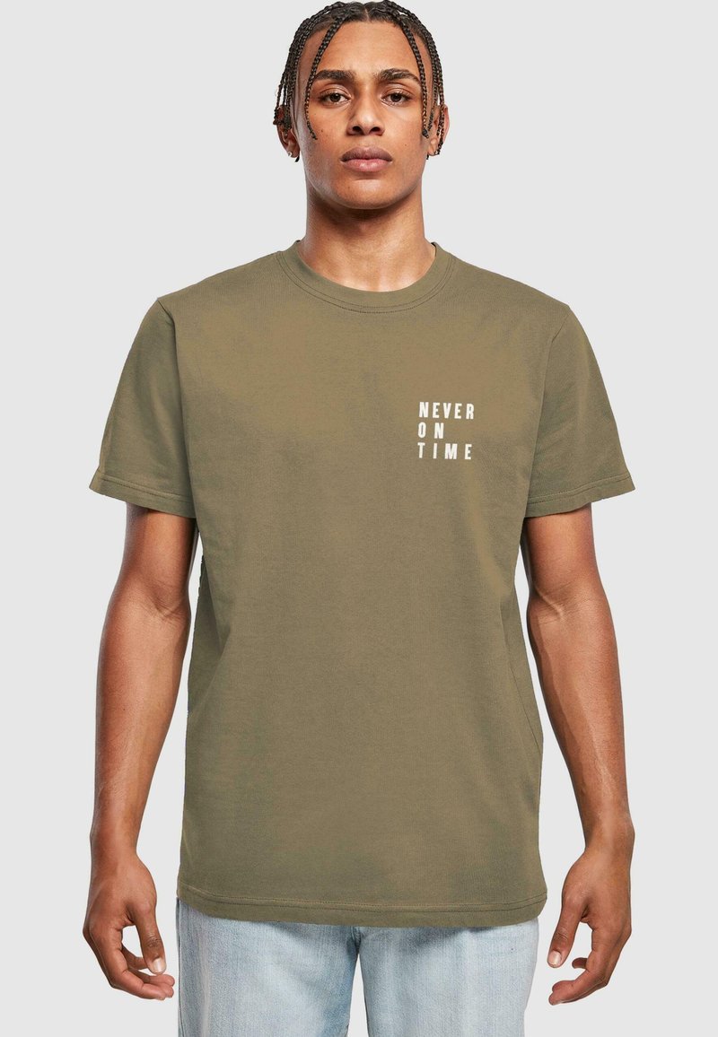 Oliven grøn bomulds T-shirt med teksten "ALDRIG TIL TID" i hvid på venstre bryst. Kortærmet og rund hals design.