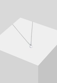 Silberne Anhänger-Halskette mit einem runden Charm, ausgestattet mit einer zarten Kette und glatter Textur, vor einem minimalistischen Hintergrund präsentiert.