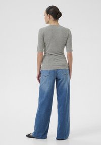 Grå, tætsiddende top med korte ærmer, parret med løse, blå denim jeans. Outfittet har et enkelt design og en glat tekstur.