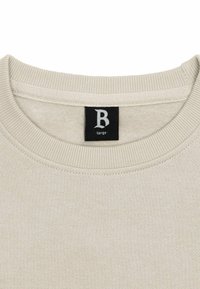 Vaaleanbeige collegepaita, jossa on pyöreä kaula-aukko, ribbaustuet ja label, jossa on musta kirjain "B" koko suurena. Pehmeä rakenne.
