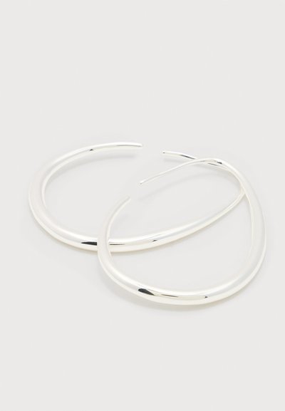 Ζεύγος λείων, γυαλιστερών ασημένιων ανοιχτών σκουλαρικιών με ελαφρώς οβάλ σχήμα πάνω σε απλό λευκό φόντο.