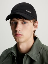 Cappellino da baseball nero in tessuto, con un piccolo etichetta logo Calvin Klein. Il cappellino ha una visiera curva e dettagli di cucitura sottili.