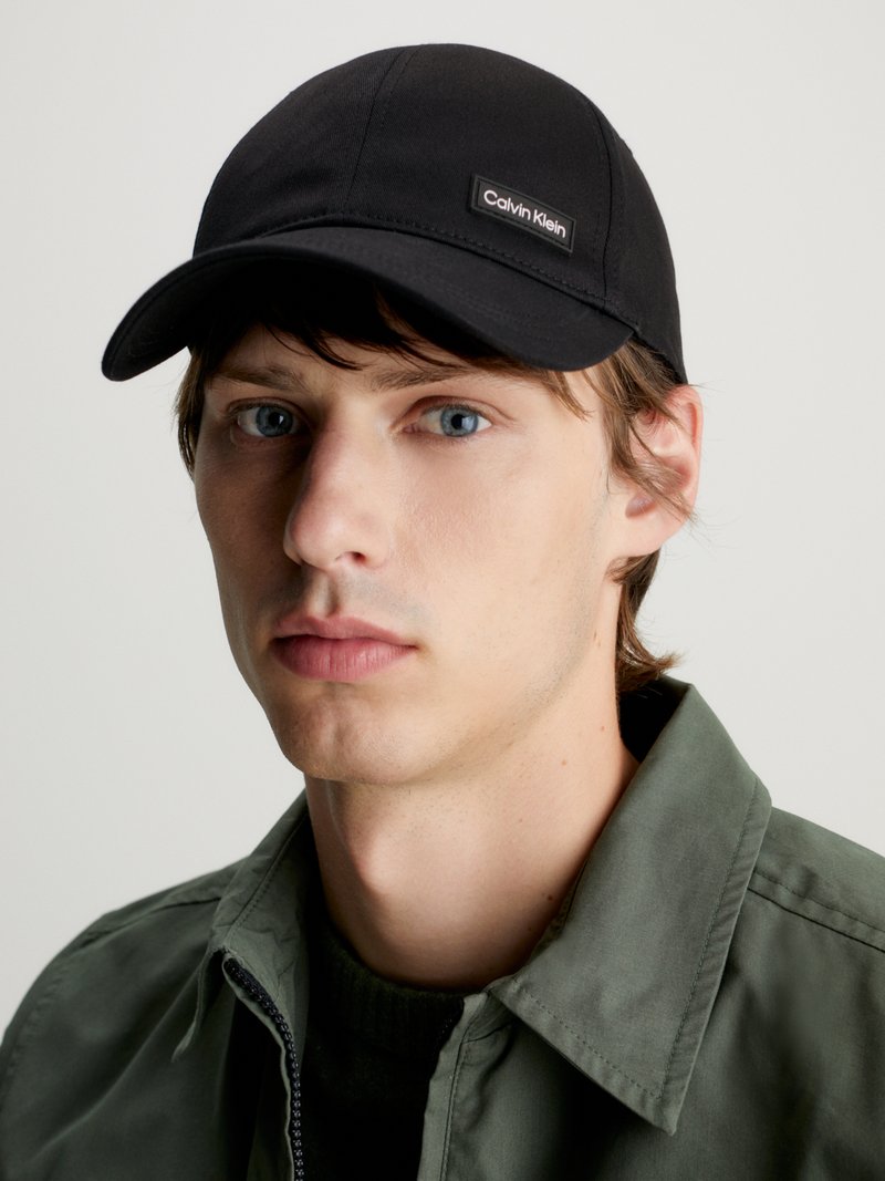 Cappellino da baseball nero in tessuto, con un piccolo etichetta logo Calvin Klein. Il cappellino ha una visiera curva e dettagli di cucitura sottili.