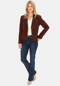 Bordowy żakiet z teksturowanym przodem, pięcioma guzikami i wyciętym kołnierzem; w połączeniu z dopasowanymi ciemnymi dżinsami i beżowymi szpilkami.