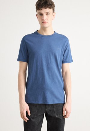 Maglietta blu a maniche corte realizzata in tessuto morbido, con collo a giro e un sottile logo "BOSS" sul petto. Indossata con jeans scuri.