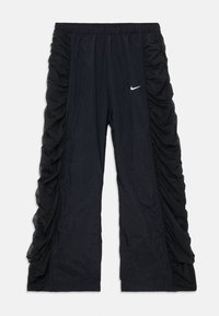 Čierne športové nohavice s bočnými gumičkami, elastickým pásom a malým bielym logom Nike na prednej strane. Ľahký materiál.