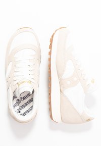 Baskets en suède beige et mesh blanc avec semelles en caoutchouc, dotées d'accents dorés et d'un logo, à bout rond et finition texturée.