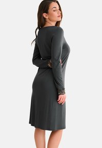 Robe grise à manches longues avec une silhouette ajustée, ornée de détails en dentelle sur les manches et d'un tissu lisse et texturé.