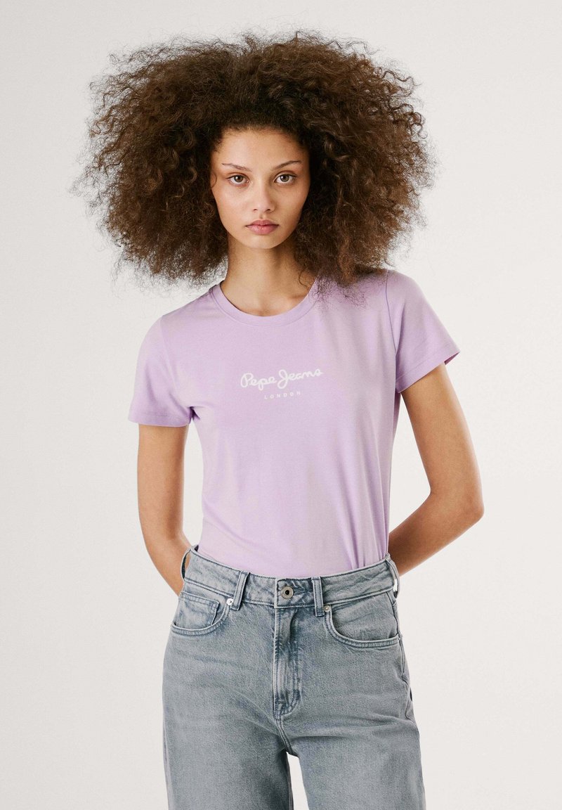 Gaiši violetas īsām piedurknēm T-krekls ar "Pepe Jeans London" logo baltā krāsā. Saskaņots ar gaiši ziliem augsta vidukļa džinsiem.
