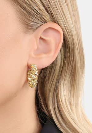 Pendientes de aro en tono dorado con un diseño retorcido e interconectado. La superficie presenta un acabado texturizado y acentos brillantes para un detalle adicional.
