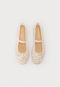 Ballerine in pizzo beige con punta rotonda e cinturino alla caviglia. Sovrapposizione in pizzo testurizzato con motivi floreali. Rivestimento interno liscio.