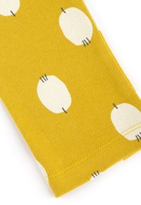 Yellow fabric featuring white oval shapes with dark outlines, displayed at an angle to show texture and stitching details.
