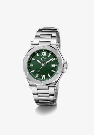 Ceas de mână din oțel inoxidabil cu cadran verde, marcaje argintii pentru ore, cifre romane XII și VI, afișaj pentru dată și brățară din zale metalice.