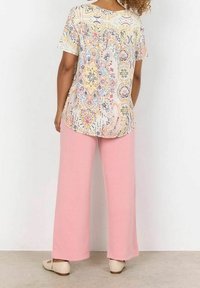 Lehká květinová blůzka s krátkými rukávy, vyznačující se pastelovými barvami a složitými vzory. Vybavená volnými růžovými kalhotami a béžovými botami.