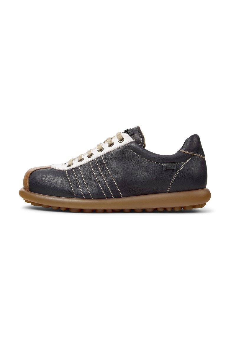 Black leather sneaker with white toe cap, brown rubber sole, and beige laces. Features three decorative stripes on the side and subtle stitching.