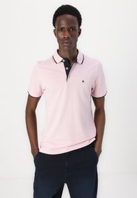 Lichtroze polo shirt met marineblauwe kraag en knoopsluiting. Korte mouwen met marineblauwe accenten. Draag met donker marineblauwe broek. Kleurrijk, casual ontwerp.