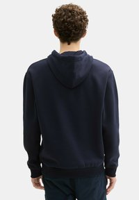 Sudadera con capucha de color azul marino, fabricada en una mezcla de algodón, con puños y dobladillo acanalados, corte relajado, vista trasera que muestra la capucha y los detalles de las costuras.