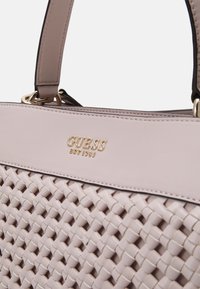 Lys pink vævet håndtaske med en glat kunstlæder top og guld logo accenter. Den har dobbelte håndtag og detaljeret syning.