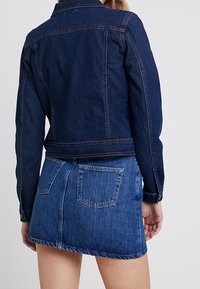 Mörkblå denimjacka med en figursydd design, med en klassisk krage och ryggåke, i kombination med en matchande denim minikjol.