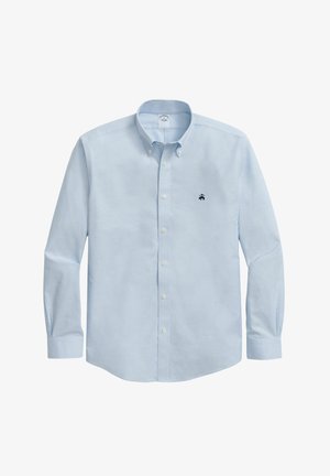 Jasnoniebieska koszula z długim rękawem, uszyta z gładkiego materiału, z małym ciemnym logo na lewej stronie klatki piersiowej.