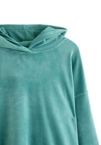 Turkusowa bluza z kapturem z miękkiego, teksturowanego materiału; ma luźny krój, zaokrąglony dekolt i opadające ramiona.
