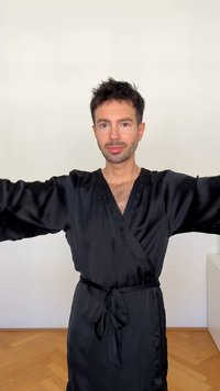 Robe in satin nero con maniche lunghe, vita legata e scollatura a V profonda. Texture liscia ed elegante drappeggio. Design semplice e uniforme.