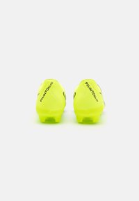 Botas de fútbol de color amarillo neón con un upper sintético liso, que presenta acentos negros y un diseño de perfil bajo. Clavos atornillables para tracción.