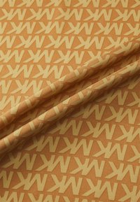 Stof met een geometrisch patroon van in elkaar grijpende gele "K"-vormen op een oranje achtergrond. Gladde textuur, gevouwen met zichtbare naden.