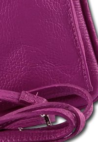 Paarse leren tas met een textuur, voorzien van een bijpassende schouderriem. De randen zijn netjes afgewerkt, wat een slank design benadrukt.