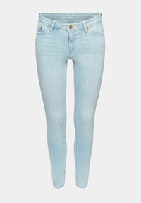 Jean skinny bleu clair avec fermeture à boutons et zip à l'avant, design à cinq poches et détails à rivets en cuivre.