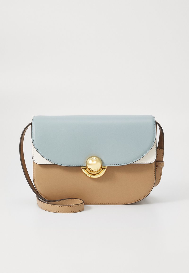 Bolso bandolera con una tapa de color azul claro, cuerpo beige, acentos blancos y herrajes circulares dorados. Textura de cuero suave, correa ajustable.