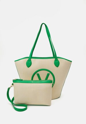 Beige geweven totebag en bijpassende kleinere pouch met groene biezen, handgrepen en een groen rond logo op de voorkant van de totebag.