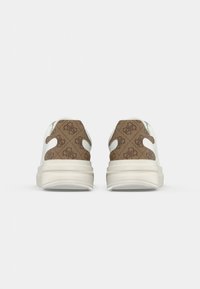 Un paio di sneakers bianche viste da dietro, con pannelli del tallone a motivo marrone e un design del logo ripetuto.