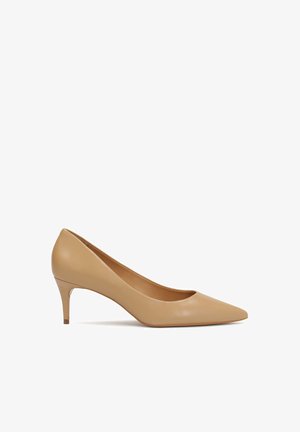 Beige hoge hakken pump met een spitse neus, een zachte leren bovenkant en een slanke, ongeveer 7,5 cm hoge hak. Eenvoudig en strak ontwerp.
