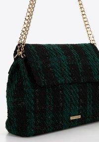 Black and green tweed handbag with a textured finish, gold chain strap, flap closure, and a brand logo detail on the front.