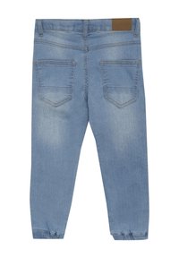 Vaaleansiniset denimpantsit kapeilla lahkeilla, joissa on kaksi takataskua, hieno haalistuminen ja joustavat hihnat nilkoissa. Vyötäröllä ruskea nahkapatukka.