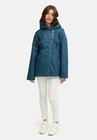 Niebieska kurtka dżinsowa z kapturem, zamkiem z przodu i lekkim ociepleniem. Połączona z białymi obcisłymi spodniami i białymi tenisówkami.