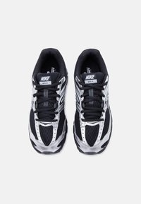 Ζευγάρι μαύρα και ασημί αθλητικά παπούτσια Nike Moto 2K, ορατά από πάνω, με κορδόνια, πλέγμα και λογότυπο στη γλώσσα και στα πλευρά.