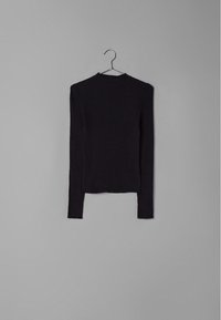 Haut noir à manches longues côtelé avec un col montant et un ourlet légèrement court, présentant une texture lisse et une coupe ajustée. Suspendu à un cintre en métal.