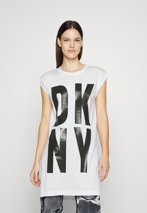 T-shirt bianco in cotone con grande stampa nera "DKNY". Maniche corte, vestibilità rilassata, orlo dritto. Sfondo semplice e chiaro.