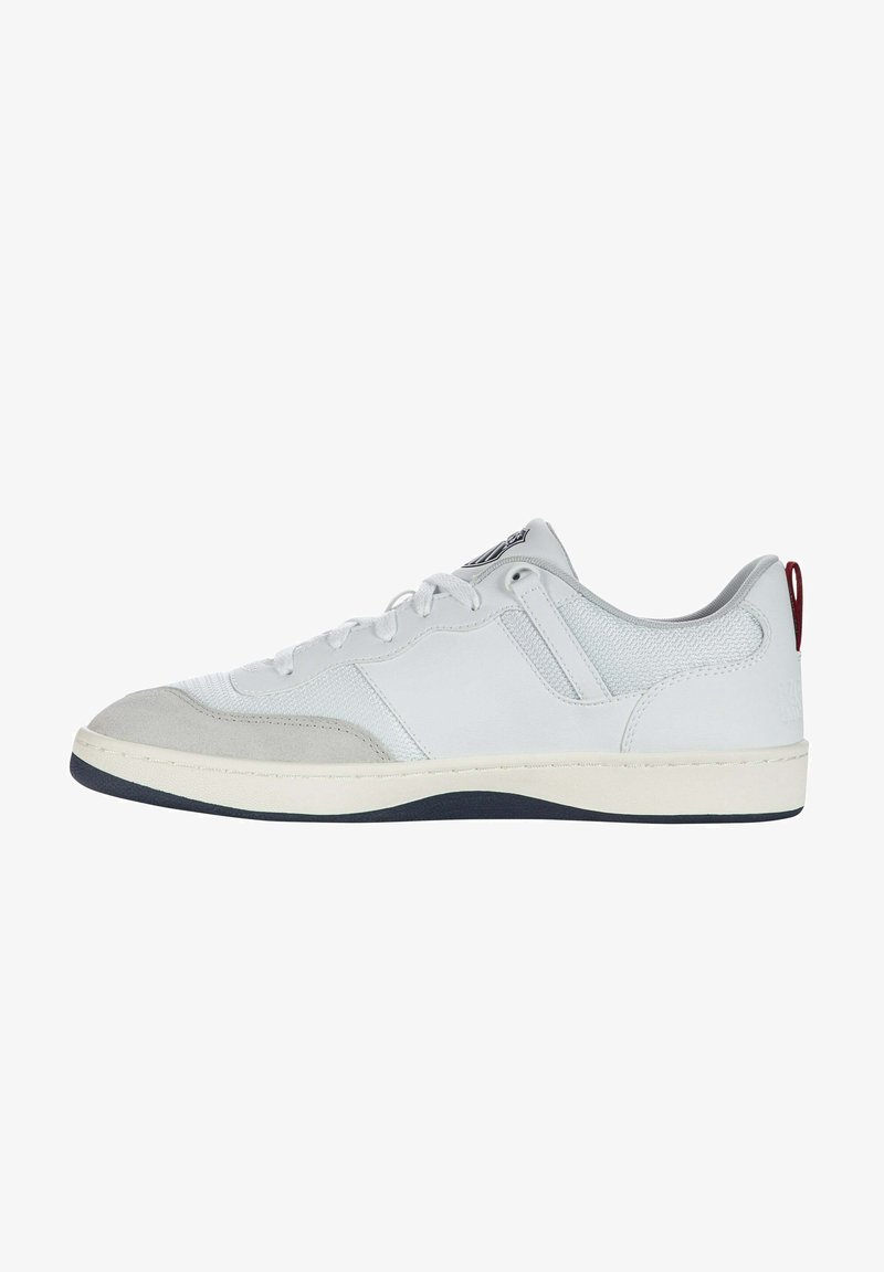 Fehér sneaker szürke velúr részletekkel, sima bőrrel és hálós panelekből. Kerek orral, lapos talppal és piros sarkú füllel rendelkezik.